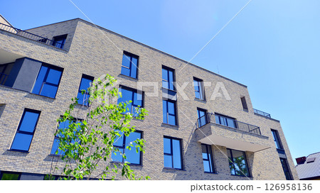 Eco architecture. Green tree and new residential building. Harmony of nature and modernity. Modern apartment building with new apartments in a green residential area. 126958136