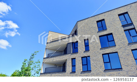Eco architecture. Green tree and new residential building. Harmony of nature and modernity. Modern apartment building with new apartments in a green residential area. 126958137