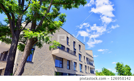 Eco architecture. Green tree and new residential building. Harmony of nature and modernity. Modern apartment building with new apartments in a green residential area. 126958142