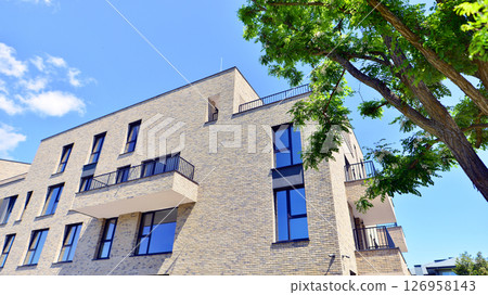 Eco architecture. Green tree and new residential building. Harmony of nature and modernity. Modern apartment building with new apartments in a green residential area. 126958143