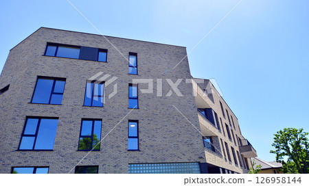 Eco architecture. Green tree and new residential building. Harmony of nature and modernity. Modern apartment building with new apartments in a green residential area. Eco architecture. Green tree and new residential building. Harmony of nature and modernity. Modern apartment building with new apartments in a green residential area. 126958144