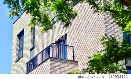 Eco architecture. Green tree and new residential building. Harmony of nature and modernity. Modern apartment building with new apartments in a green residential area. Eco architecture. Green tree and new residential building. Harmony of nature and modernity. Modern apartment building with new apartments in a green residential area. 126958151