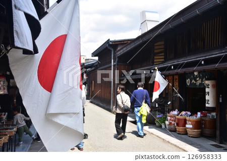 Old streetscape of Takayama city, Gifu prefecture, Japan. Stores displaying Japanese flags and tourists enjoying shopping during the Spring Takayama Festival. 126958333