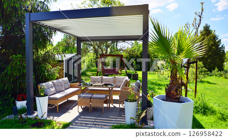 Modern aluminum pergola with stylish garden furniture in a beautiful garden. 126958422