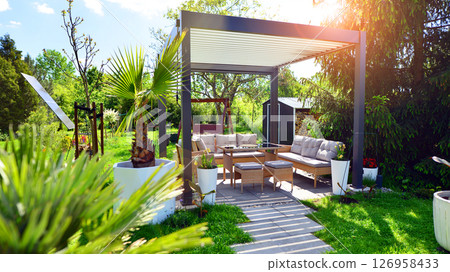 Modern aluminum pergola with stylish garden furniture in a beautiful garden. 126958433