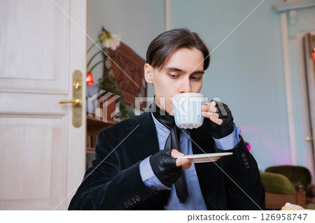 young elegant rich heir man drinking morning coffee in a sophisticated room decorated with vintage elements in his mansion 126958747