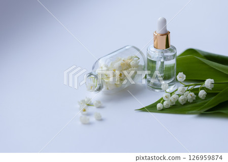 Glass bottle of lily of the valley essential oil with fresh flowers 126959874
