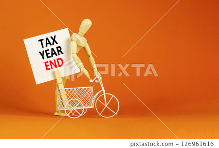 Tax year end symbol. Concept words Tax year end on beautiful white card. Beautiful orange background. Businessman model. Business tax year end concept. Copy space. Tax year end symbol. Concept words Tax year end on beautiful white card. Beautiful orange background. Businessman model. Business tax year end concept. Copy space. 126961616