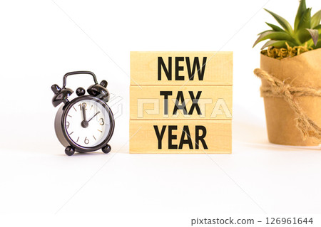 New tax year symbol. Concept words New tax year on beautiful wooden blocks. Beautiful white background. Black alarm clock. Business new tax year concept. Copy space. New tax year symbol. Concept words New tax year on beautiful wooden blocks. Beautiful white background. Black alarm clock. Business new tax year concept. Copy space. 126961644