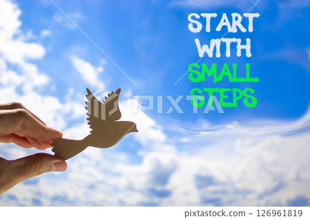 Start with small steps symbol. Concept words phrase Start with small steps on beautiful blue sky. Businessman's hand. Beautiful blue sky background. Business Start with small steps concept. Copy space Start with small steps symbol. Concept words phrase Start with small steps on beautiful blue sky. Businessman's hand. Beautiful blue sky background. Business Start with small steps concept. Copy space 126961819