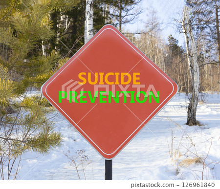 Suicide prevention symbol. Concept words Suicide prevention on beautiful red road sign. Beautiful winter forest background. Psychological suicide prevention concept. Copy space. Suicide prevention symbol. Concept words Suicide prevention on beautiful red road sign. Beautiful winter forest background. Psychological suicide prevention concept. Copy space. 126961840