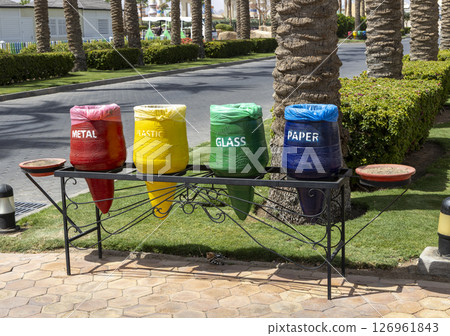 Color-coded recycle bins in Egypt hotel resort dedicated to separate waste collection for plastic glass metal and paper highlighting recycling and environmental responsibility. Environmental concept. Color-coded recycle bins in Egypt hotel resort dedicated to separate waste collection for plastic glass metal and paper highlighting recycling and environmental responsibility. Environmental concept. 126961843