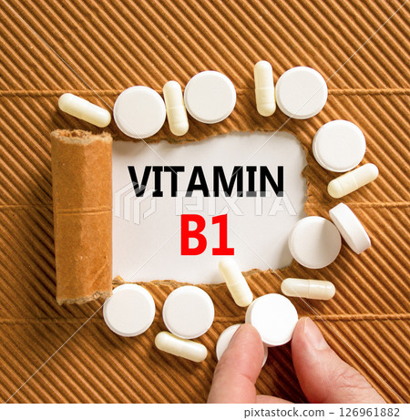 Vitamin B1 symbol. Concept words Vitamin B1 on beautiful white paper. White pills tablets. Doctor's hand. Beautiful brown background. Medical healthy lifestyle Vitamin B1 concept. Vitamin B1 symbol. Concept words Vitamin B1 on beautiful white paper. White pills tablets. Doctor's hand. Beautiful brown background. Medical healthy lifestyle Vitamin B1 concept. 126961882
