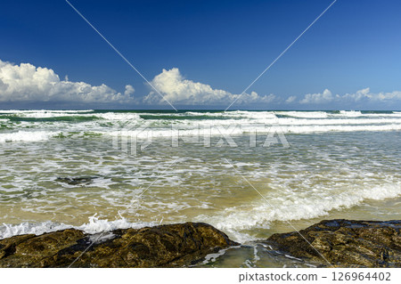 Small waves on a deserted and rocky beach 126964402