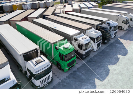 Row of semi trucks, one truck is green. Symbolizing a sustainable transport 126964620