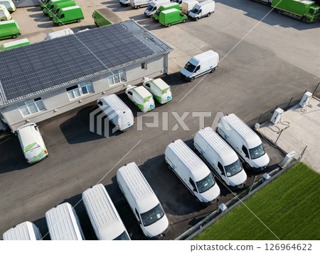 Rows of white electric delivery vans at charging stations for electric vehicles 126964622