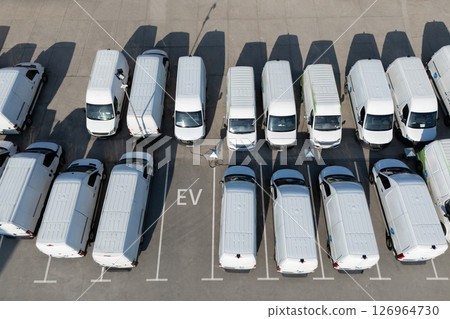 Rows of white electric delivery vans at charging stations for electric vehicles 126964730