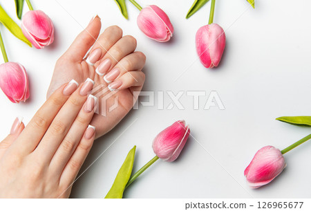 Woman showing french manicure near pink tulips on white background Woman showing french manicure near pink tulips on white background 126965677