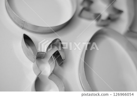 Black and white close-up photo of metal cookie cutters arranged on a flat white surface 126966054