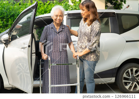 Caregiver help Asian elderly woman disability patient get in her car. 126966111