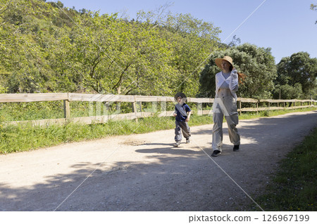 Mother and son walking on a country road in summer Mother and son walking on a country road in summer 126967199