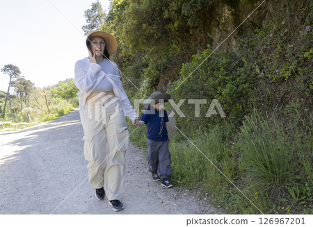Mother and son walking on a path, enjoying nature and talking on the phone Mother and son walking on a path, enjoying nature and talking on the phone 126967201