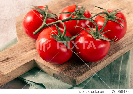 Fresh red tomatoes on a branch, on a wooden chopping board, close-up, no people, 126968424