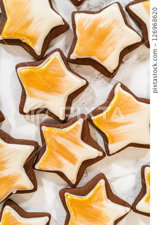 A collection of gingerbread star cookies decorated with royal icing and painted with vibrant gold luster dust, beautifully arranged for a festive look. A collection of gingerbread star cookies decorated with royal icing and painted with vibrant gold luster dust, beautifully arranged for a festive look. 126968620