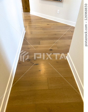 Simple and clean view of a light wood plank hallway with white baseboards. Perfect for real estate listings or renovation guides. Simple and clean view of a light wood plank hallway with white baseboards. Perfect for real estate listings or renovation guides. 126968650
