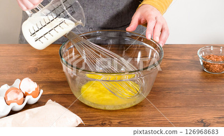 In a glass mixing bowl, a large hand whisk expertly blends the ingredients for a delectable gingerbread bundt cake with caramel frosting. In a glass mixing bowl, a large hand whisk expertly blends the ingredients for a delectable gingerbread bundt cake with caramel frosting. 126968683