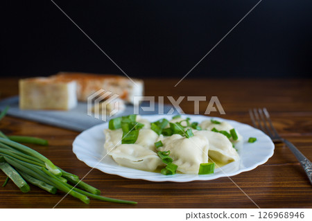 Delicious Ukrainian dumplings with steam and green onions Delicious Ukrainian dumplings with steam and green onions 126968946