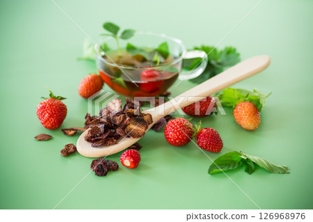 Bright strawberry tea in transparent glassware on a green background Bright strawberry tea in transparent glassware on a green background 126968976