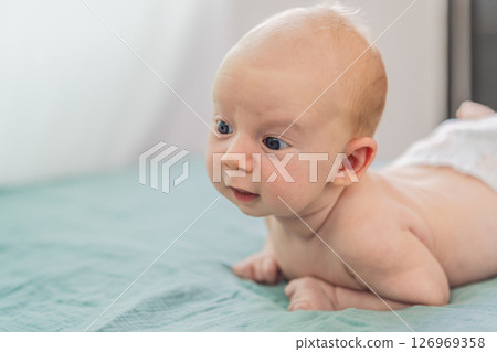One-month-old baby lying on tummy and curiously observing surroundings. Infant tummy time for neck strength, cognitive development, and early exploration. Parenting and newborn growth concept 126969358