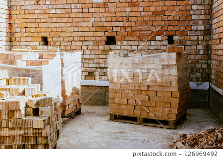 Building materials are on floor, stack red bricks. Production high-quality ceramic brick matte, reddish, porous fracture. Brick used for laying foundation. Purchase building material at hardware store Building materials are on floor, stack red bricks. Production high-quality ceramic brick matte, reddish, porous fracture. Brick used for laying foundation. Purchase building material at hardware store 126969492
