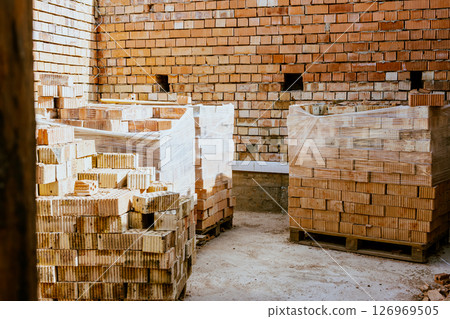 Building materials are on floor, stack red bricks. Production high-quality ceramic brick matte, reddish, porous fracture. Brick used for laying foundation. Purchase building material at hardware store 126969505