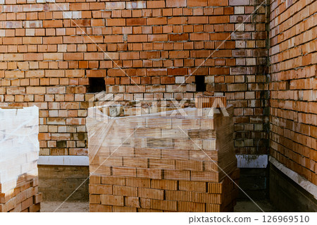Building materials are on floor, stack red bricks. Production high-quality ceramic brick matte, reddish, porous fracture. Brick used for laying foundation. Purchase building material at hardware store 126969510