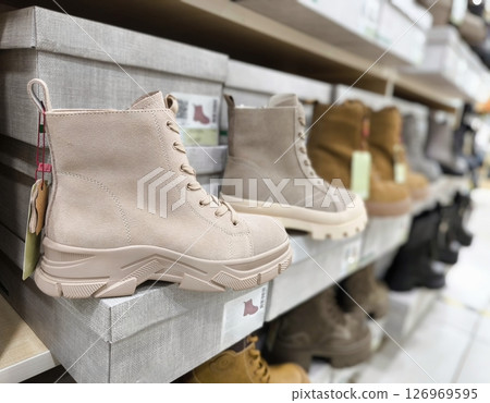 shoe store filled with various styles of footwear. Women's autumn shoes on the counter in the store. Beige boots. shoe store filled with various styles of footwear. Women's autumn shoes on the counter in the store. Beige boots. 126969595