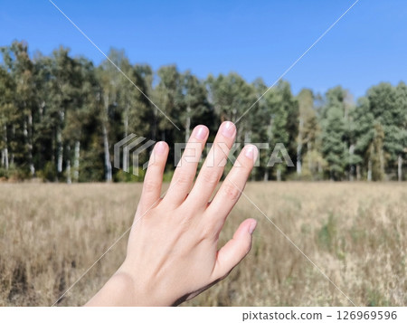 woman's hand on the background of a natural landscape. Unity with nature, Save the planet. 126969596