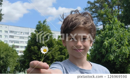 boy holding one chamomile. happy teen with a daisy in his hands. Summer outdoors time. boy holding one chamomile. happy teen with a daisy in his hands. Summer outdoors time. 126969598
