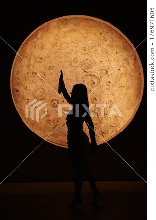 Silhouette of a beautifully designed figure painted against a bright moon in the night sky Silhouette of a beautifully designed figure painted against a bright moon in the night sky 126971603