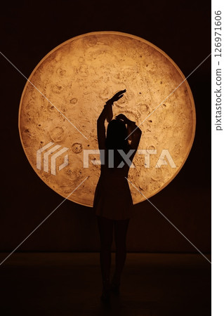The beautiful silhouette of a dancer moves gracefully against a stunning moonlit backdrop The beautiful silhouette of a dancer moves gracefully against a stunning moonlit backdrop 126971606