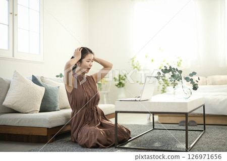 A woman in her twenties staring at a laptop computer with a troubled look on her face 126971656