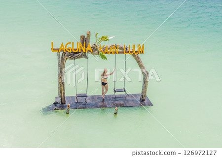 Young woman swinging over the turquoise waters of Kaan Luum Lagoon, Quintana Roo, Mexico. Relaxation and tropical adventure concept 126972127