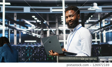 Happy data center admin uses node tree programming on laptop to identify equipment performance issues. Cheerful server farm worker reviews data analysis graph to minimize hardware failures, camera B Happy data center admin uses node tree programming on laptop to identify equipment performance issues. Cheerful server farm worker reviews data analysis graph to minimize hardware failures, camera B 126972189