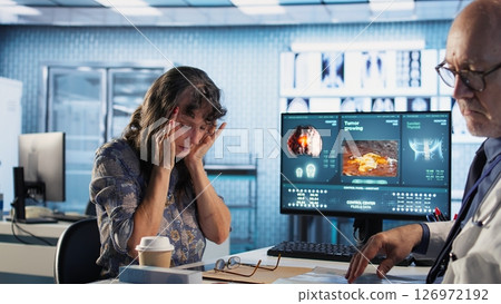 General practitioner consulting old woman with severe migraine at the clinic, prescribing recovery plan on health insurance. Senior medic having a patient with headache and inflammation. Camera A. 126972192