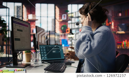 Customer support agent arriving at work, entering office, assisting customers with inquiries. Call center employee sitting down at PC desk, starting account management tasks, camera B 126972237