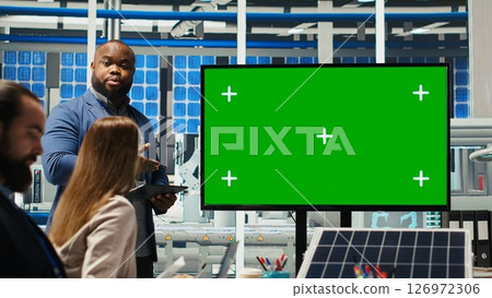 Managers in office reviewing solar technology reports on green screen monitor. Shareholders using mockup display, discussing investment opportunities in green energy production, camera B 126972306