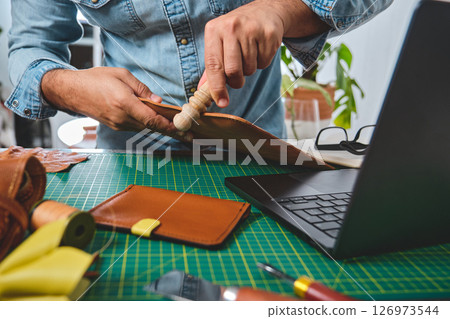 Shoemaker working leather using burnishing tool in his workshop 126973544
