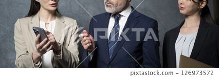 A man with grey hair who looks like a company president and a young woman who looks like a secretary are having a meeting. 126973572