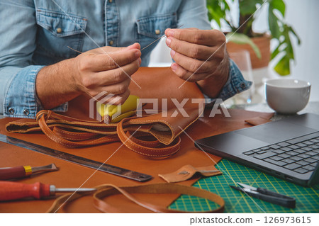 Craftsman sewing leather bag in small business workshop 126973615